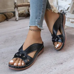 Gros plan sur les sandales compensées noires rétro avec des fleurs et bout ouvert chic