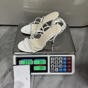 Mesure du poids de sandales blanches à talons hauts et lacets sur une balance