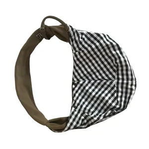 Close-up detail of black and white gingham pet sling carrier bag with brown shoulder strap