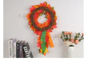 Autumn harvest wreath with vibrant maple leaves hanging on a white wall above books.