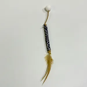 Natural silvervine cat chew stick toy with feather and white pom-pom detail view