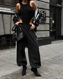 Urban street style view of a black oversized tracksuit with side stripes and a studded bag