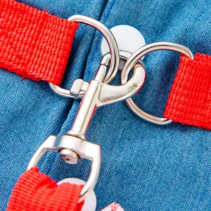 Close-up of a durable metal snap hook and dual D-rings on blue denim pet harness