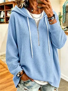 Detailed view of a blue waffle knit hooded sweatshirt with a quarter zipper closure.