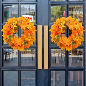 Decorative autumn door wreaths featuring maple leaves and pumpkins on a black glass door