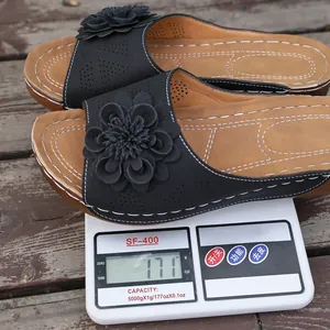 Detail of a lightweight black floral wedge slipper being weighed on a scale