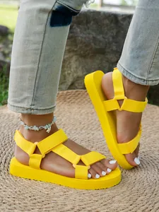 Sandales à plateforme jaune vif avec brides velcro pour femmes dans un décor estival.