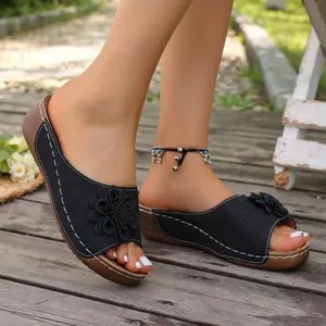 Detailed side view of black wedge sandals with a 3D flower and white stitching