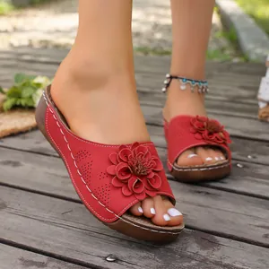 Detailed view of women's red wedge slippers featuring an elegant flower decoration.