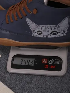 Detail van een blauwe hoge schoen met kattenprint die 344,3 g weegt op een weegschaal