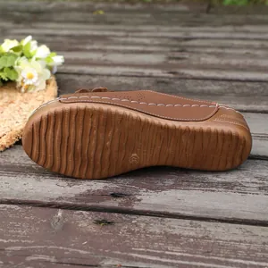 Detailed macro view showing the non-slip rubber sole and wedge heel of brown flower sandals