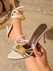 Eleganti sabot bianchi con tacco alto e un grande fiore in metallo dorato applicato
