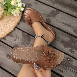 Detail view of brown wedge sandals featuring an elegant 3D flower and laser-cut patterns.