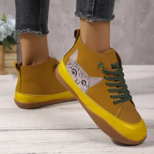 Detail van mosterdgele hoge schoenen met kattenprint en groene veters.