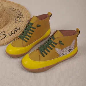 Detailopname van mosterdgele hoge sneakers met een schattige kat en groene veters