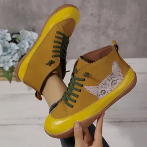 Detailopname van gele hoge damesschoenen met schattig kattenpatroon en groene veters.