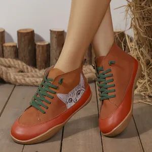 Zijaanzicht detail van oranje en bruine hoge schoenen met een schattige kattenillustratie.
