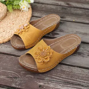 Detailed view of summer yellow wedge sandals featuring a large ornate floral decoration.