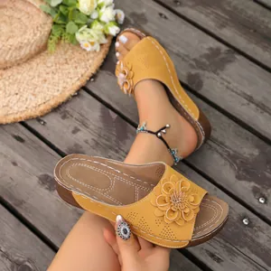 Close-up view of stylish yellow wedge sandals with decorative flower and laser-cut details