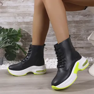 Schwarze PU-Leder-Plateau-Sneaker mit neongrünen Akzenten an einem Model getragen