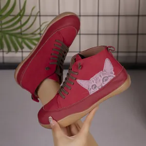 Detail van rode hoge sneakers met een schattige kattenprint en platte rubberen zolen.