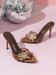 Dettaglio dell'elegante fiore in metallo dorato su questi sandali mule a spillo