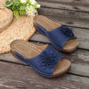 Detailed view of navy blue wedge sandals with 3D floral decoration on wooden floor