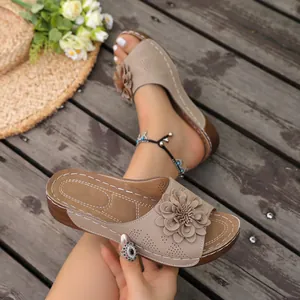 Close-up of beige wedge sandals with decorative flower and contrast white stitching