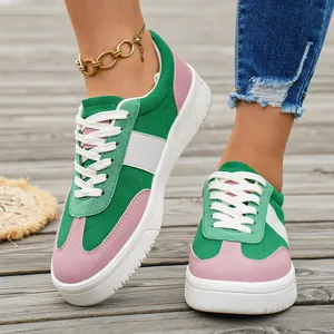 Gros plan de baskets pour femmes en daim vert et rose sur une terrasse en bois