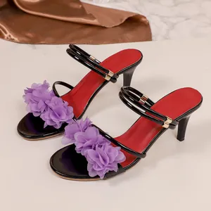 Detailed view of high heel sandals featuring purple flower accents and red footbed