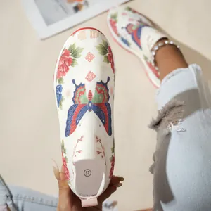 Gros plan de baskets blanches en maille à enfiler avec motifs fleurs et papillons