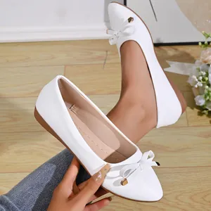 Elegant white pointed-toe flats with bow detail and gold accents, French style design.