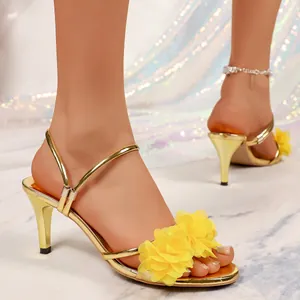 Detail view of gold stiletto sandals featuring delicate yellow floral embellishments.
