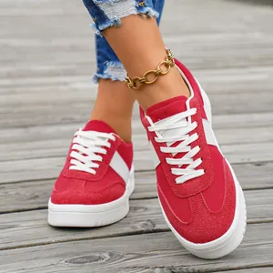 Baskets femme en daim rouge avec lacets blancs sur fond de bois