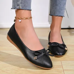 Close-up of elegant black pointed-toe ballet flats featuring a bow with gold tips