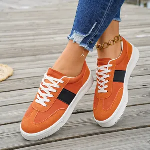 Vue détaillée des baskets basses en daim orange sur un fond de terrasse en bois