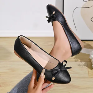 Close-up detail of stylish black pointed-toe ballet flats featuring an elegant bow decoration.