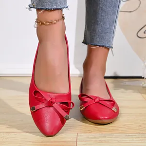 Close-up of red pointed-toe ballet flats featuring elegant bow and golden accents