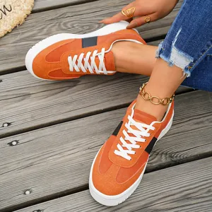 Gros plan détaillé sur des baskets en daim orange pour femme sur un fond en bois