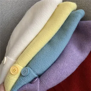 Close-up of soft knit cardigans in pastel colors showing fine texture and matching buttons.