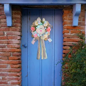 Easter rabbit wreath with pink roses and colorful ribbons hanging on a rustic blue door