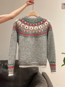 Detailed macro view of gray Fair Isle knit sweater featuring colorful retro floral patterns