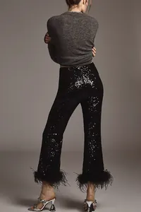 Close-up of elegant black sequin trousers featuring luxury feather fringe at hems