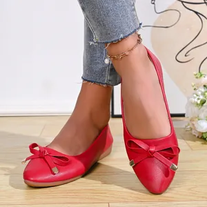 Elegant red pointed-toe ballet flats featuring a decorative bow on textured faux leather