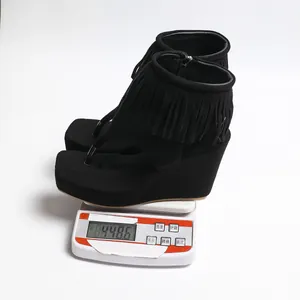 Sandales compensées à franges noires pour femmes pesées sur une balance numérique