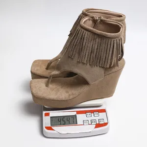 Détail de sandales compensées à franges montrant le poids du produit sur une balance