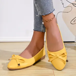 Close-up of elegant yellow pointed-toe ballet flats with bow detail and gold tips