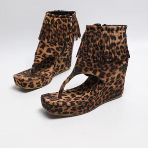 Vue détaillée des sandales à talons compensés léopard avec franges western et fermeture éclair.