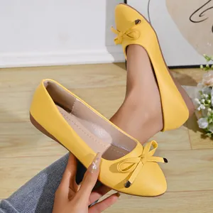 Close-up of yellow pointed-toe flats with bow detail and textured leather finish