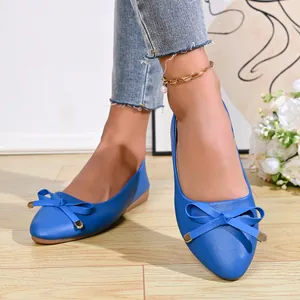 Close-up of blue pointed-toe ballet flats featuring a decorative bow with gold tips.